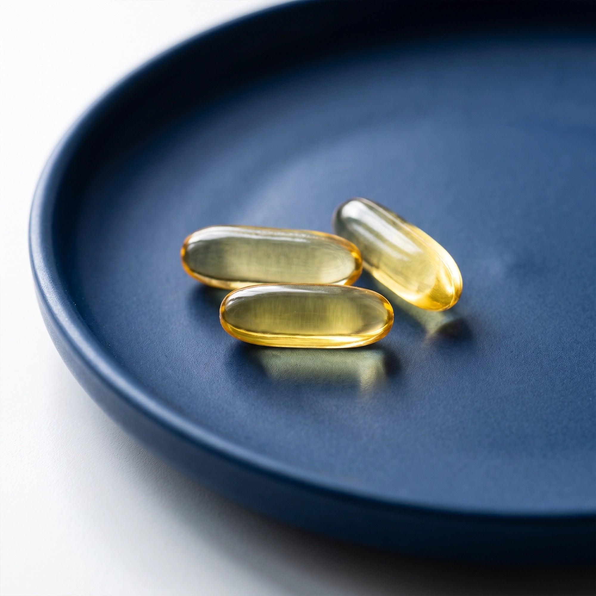 Cápsulas de Omega-3 TRESSO Suplementos color ámbar sobre plato azul